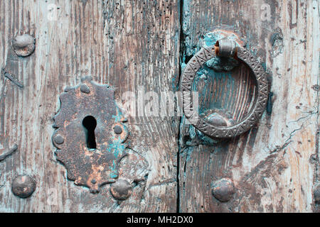 Close-up Fragment des alten hölzernen Tür mit Oxidiertem Schlüsselloch geschmiedete Nieten und Stahl Klopfer. Textur aus antikem Holz und Tür detail. Stockfoto