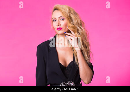 Wunderschöne junge blonde Frau in Schwarz Elegante modische Kleidung auf rosa Hintergrund posiert. Stockfoto