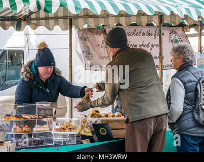 Mann kauft Kuchen im Freien Markt ausgeht, Haddington Farmers Market, Place d'Aubigny, Court Street, East Lothian, Großbritannien im Winter Tag Stockfoto