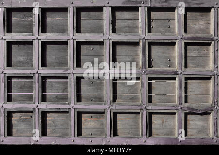 Die Textur eines antiken hölzernen Tür aus dem 16. und 17. Jahrhundert. Alte Tore aus Holz mit Metall geschmiedet Fragmente verstärkt Stockfoto