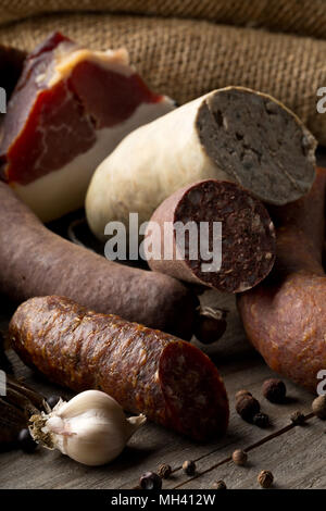 Auswahl deutscher Wurstspezialitäten hart kuriert Salami, Leberwurst (Leberwurst), Blutwurst (Blutwurst) und Speck auf dem Küchentisch Stockfoto