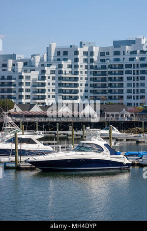Yachten festgemacht an der Marina Bay Docks, vor einer Waterfront Promenade, Restaurants und Kondominium Komplex, in Quincy, Massachusetts, USA. Stockfoto