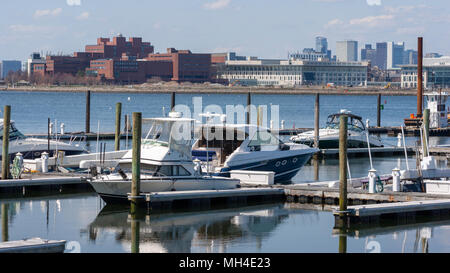 Yachten festgemacht an der Marina Bay Docks in Quincy, mit der Universität von Massachusetts und Boston Hochhäusern im Hintergrund. Stockfoto