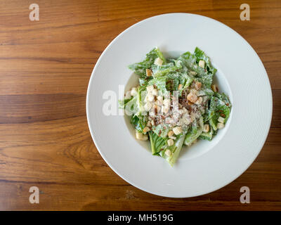 Caesar Salat auf einem weißen Teller auf Holz Tisch im Restaurant mit kopieren. Ansicht von oben. Stockfoto