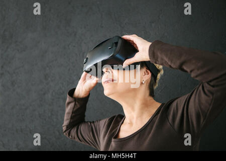 Eine ältere Frau in der virtuellen Realität Gläser. Eine ältere Person mit moderner Technologie. Stockfoto