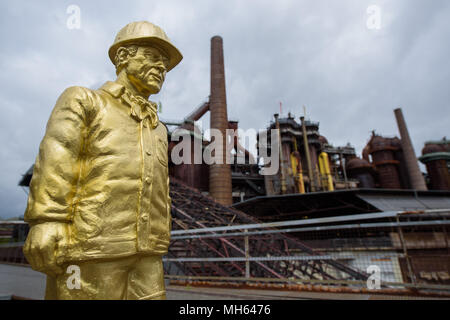 30 April 2018, Deutschland, Völklingen: Die Figur der ein Beschäftigter im Laufe der Skulptur Projekt Second Life - 100 Arbeitnehmer von Ottmar Hoerl im Weltkulturerbe Völklinger Hütte. 100 kleine rot, gold und grau Zahlen sind auf dem Gelände der ehemaligen Schmiedearbeiten ausbreiten. Foto: Oliver Dietze/dpa Stockfoto