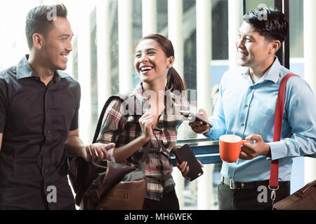 Drei jungen und freundlichen Mitarbeiter sprechen in den Morgen Stockfoto