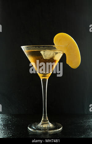 Frische Sommer appletini Cocktail in einem Martini Glas mit einem Apple Schicht auf einem schwarzen strukturierte Oberfläche mit Wassertropfen und Reflexionen. Stockfoto