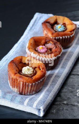 Drei leckere kleine Käsekuchen mit geschmolzener Schokolade und bunten Zucker blumen Vereisung Stockfoto