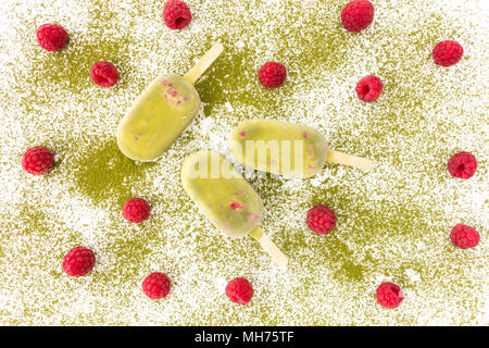 Matcha und Himbeere Eis am Stiel und frische Himbeeren auf Matcha Pulver. Ansicht von oben. Stockfoto