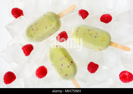 Blick von oben auf die drei hausgemachten Matcha und Himbeere Eis am Stiel auf Eiswürfel. Stockfoto