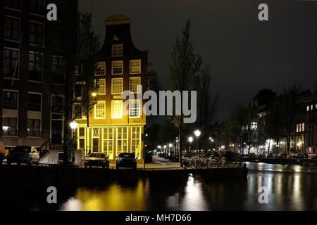 Nacht in Amsterdam: beleuchtete Gebäude in der Nähe des Flusses Kanal mit Reflexion über Wasser Stockfoto