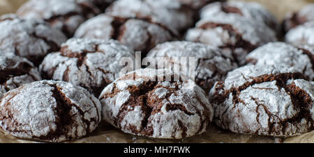 Schokolade crinkle Plätzchen mit Puderzucker Puderzucker. Gebrochene Schokolade Kekse auf dem Papier Hintergrund. Bis zu schließen. Seitenansicht Stockfoto