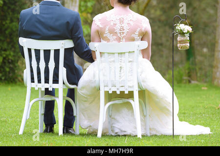 Bräutigam sitzen auf weißen woodem Stühle im Garten Unkraut jäten Zeremonie. Leere Raum für Editor's Text. Stockfoto