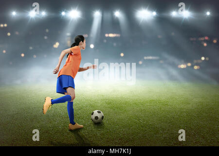 Jungen asiatischen Fußball-Spieler Frau Kick den Ball auf dem Feld Stockfoto