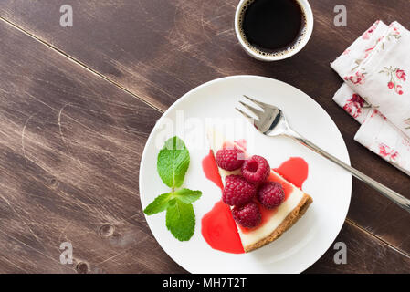 Stück Käsekuchen mit Himbeersauce und Tasse Espresso Kaffee auf Holztisch. Ansicht von oben mit Platz für Text kopieren Stockfoto