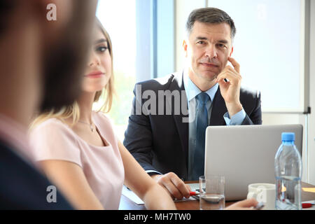 Porträt einer stattlichen Geschäftsmann, verschwommen und Kollegen in den Hintergrund. Stockfoto