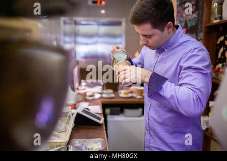 Image der Jungen barista Männer gießt Sahne im Kaffee Glas Stockfoto