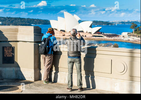 Touristen stehen auf die Schritte vor der Sydney Harbour Bridge und Pause Fotos der legendären Sydney Opera House zu nehmen. New South Wales, Austra Stockfoto
