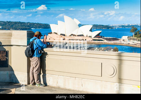 Ein Tourist steht auf die Schritte vor der Sydney Harbour Bridge und Pause Fotos der legendären Sydney Opera House zu nehmen. Sydney Australien. Stockfoto