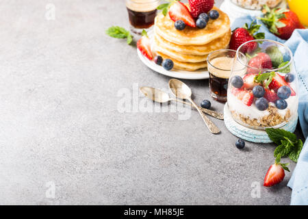 Haferflocken Müsli mit Beeren und Joghurt und panccakes auf Hellgrau konkreten Hintergrund. Gesundes Frühstück essen Konzept mit kopieren. Stockfoto
