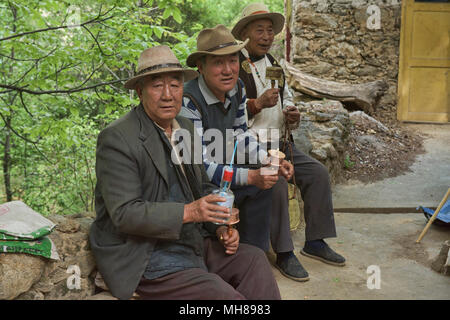 Lokale Tibeter mit Gebetsmühlen und Reiswein im Dorf Jiaju, Sichuan, China Stockfoto