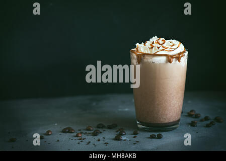 Kalte frappe Kaffee (frappuccino) mit Sahne und Karamell auf dunklem Hintergrund, kopieren. Stockfoto
