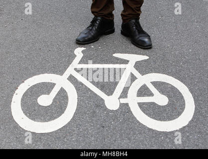 Nahaufnahme der Radweg mit dem Fahrrad symbol neben einer Person mit braunen Hosen und schwarze Schuhe stehen auf den Radweg blockieren. Stockfoto