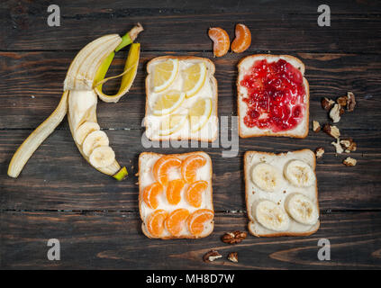 Sandwiches mit Banane, Mandarine, Marmelade, Zitrone, Brot auf Holz Hintergrund. Leckere kalte Snacks. Vegetarische Gerichte. Stockfoto