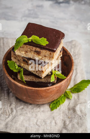 Raw vegan Kuchen mit Schokolade, einen Stapel von Scheiben geschnittenen Stücke in eine hölzerne Schüssel. Gesunde vegane Ernährung Konzept. Stockfoto