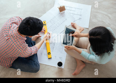 Attraktive junge asiatische erwachsenes paar Hauspläne zu betrachten. Stockfoto