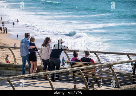 Urlauber stehen auf der Terrasse und genießen den Blick auf den Fistral Beach in Newquay in Cornwall. Stockfoto