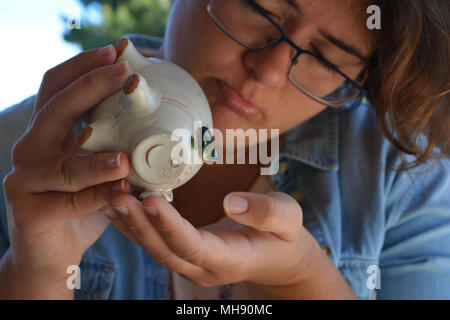 Tausendjährige Frau mit einem Keramik Sparschwein, mutlos, close-up Stockfoto