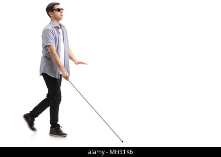 Volle Länge Profil geschossen von einem blinden Jungen Mann mit einem Stock zu Fuß auf weißem Hintergrund Stockfoto