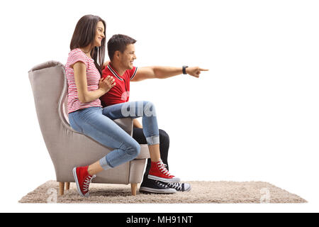 Junge Frau und ein junger Mann im Sessel sitzt mit dem jungen Mann auf weißem Hintergrund zeigen Stockfoto