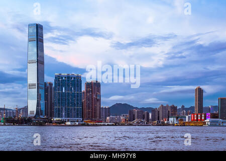 Skyline von Hongkong bei Sonnenuntergang. Blick von der Insel Hong Kong und Kowloon. International Commerce Centre. Dramatischer Himmel und die Lichter der Stadt. Stockfoto