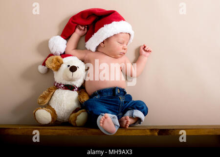 Neugeborenes Baby Boy das Tragen einer Mütze und Jeans, schlafen auf einem Regal neben Teddybären. Im Studio auf einem cremigen Hintergrund Geschossen, geschossen von abov Stockfoto