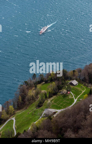 Ansicht von oben aus Schillers Balkon auf der historischen Rütliwiese mit Schweizer Flagge und nähert sich Schiff auf einer sonnigen und windigen Tag Stockfoto