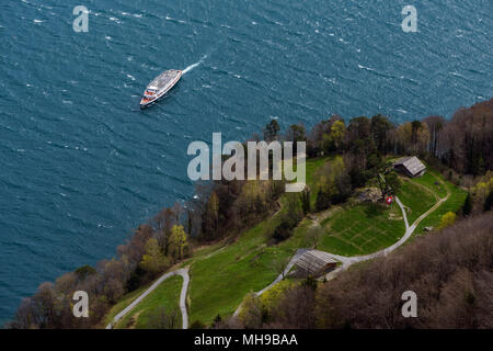 Ansicht von oben aus Schillers Balkon auf der historischen Rütliwiese mit Schweizer Flagge und nähert sich Schiff auf einer sonnigen und windigen Tag Stockfoto