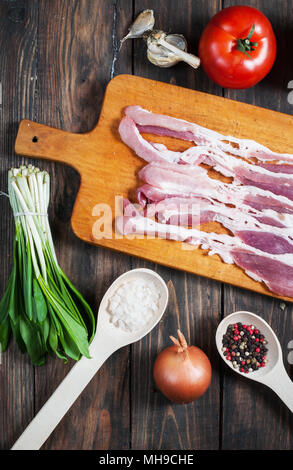 Rohen Schinken Scheiben mit Gemüse auf einem Holztisch. Ansicht von oben. Stockfoto