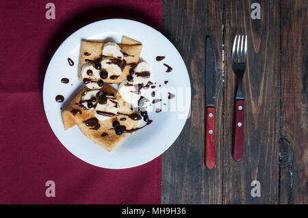 Pfannkuchen mit Schokolade und Banane auf einer hölzernen Hintergrund. Stockfoto