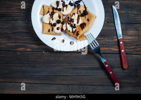 Pfannkuchen mit Schokolade und Banane auf einer hölzernen Hintergrund. Stockfoto