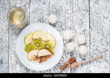 Haferflocken mit Äpfeln, Birnen, Walnüsse und Kiwi in einer weißen Schüssel. Ansicht von oben. Stockfoto