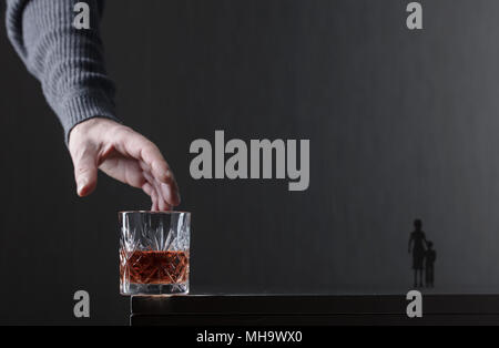 Des Menschen Hand greift nach einem Glas Alkohol. Konzeptionelle Bild zum Thema Alkoholismus. Kopieren Sie Platz für Ihren Text. Stockfoto