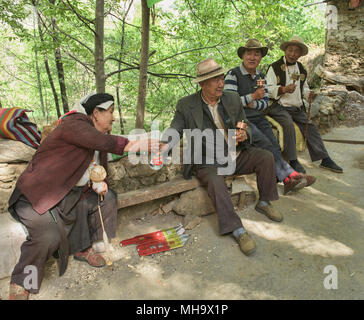 Lokale Tibeter mit Gebetsmühlen und Reiswein im Dorf Jiaju, Sichuan, China Stockfoto