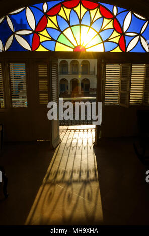 Die Morgensonne scheint durch Glasfenster und eine offene Tür in einer casa particular am Plaza Vieja, Havanna, Kuba. Stockfoto