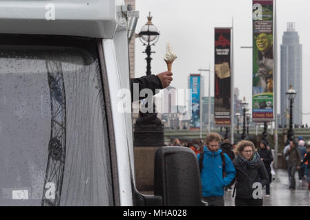 Ein Eis Verkäufer versucht, Touristen mit seine Waren auf der South Bank in London als gelbe Wetter Warnungen für schwere Regenfälle und starke Winde zu reizen für Ost-, Südosteuropa und in England ausgestellt wurden. Stockfoto