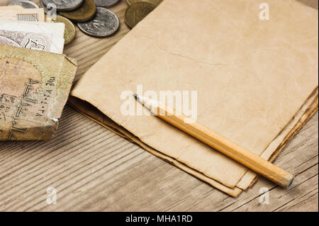 Alte Banknoten und Münzen und Bleistift auf einem Holztisch Stockfoto