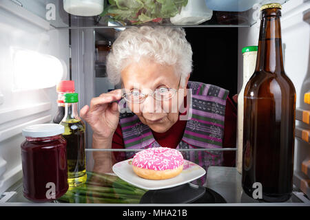 Oma entdecken ein Donut im Kühlschrank. Stockfoto