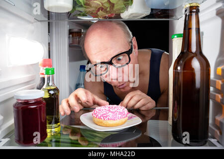 Mann entdeckt einen Donut im Kühlschrank. Stockfoto